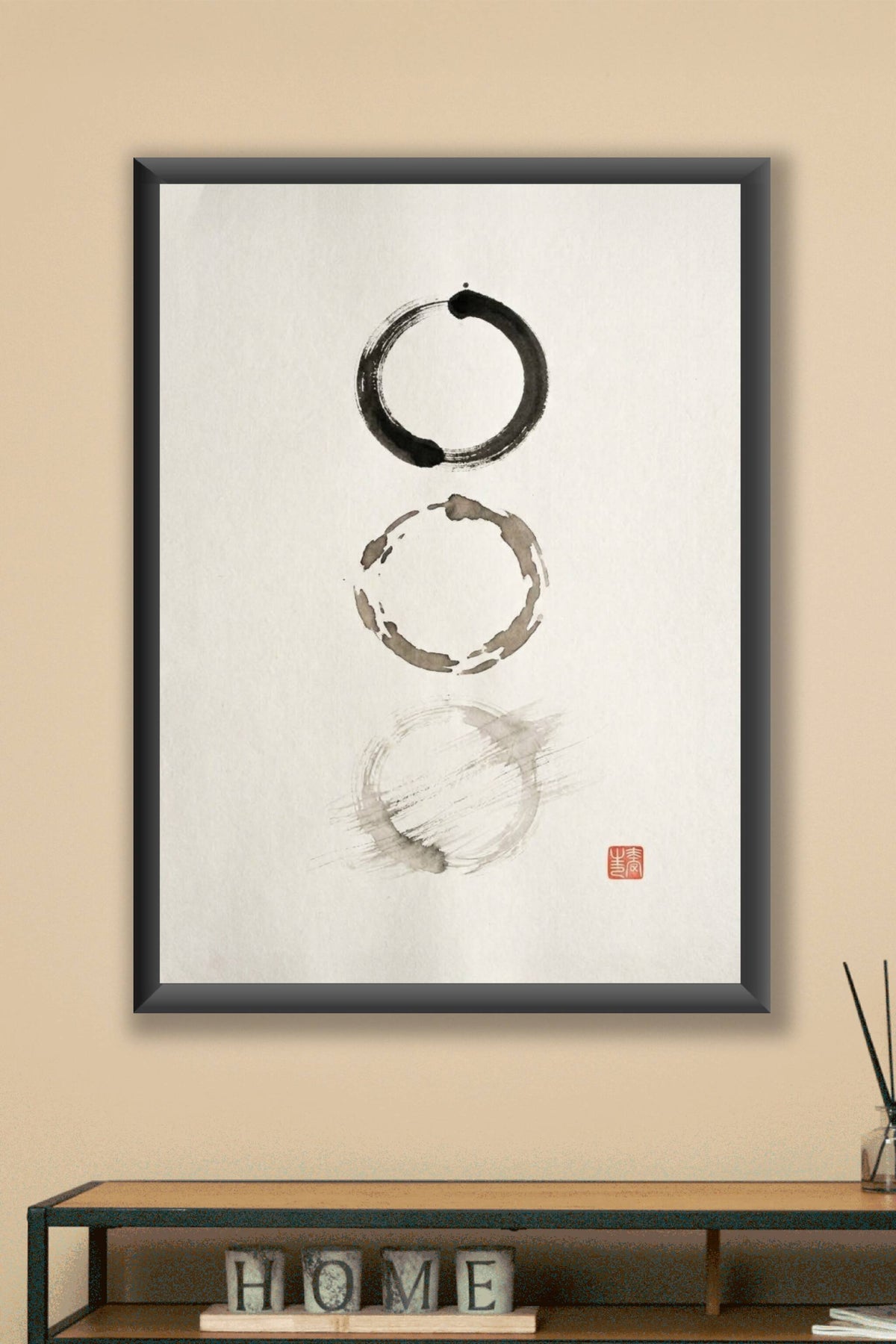 A minimalist sumi-e ink wash artwork showing three imperfect circles arranged vertically on bare paper, each brushed...
